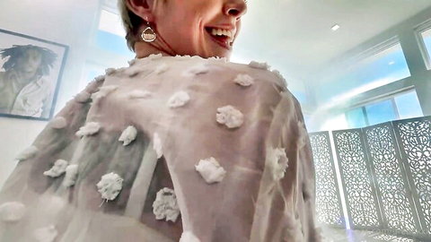 Dee Williams smiling over shoulder in sheer floral top