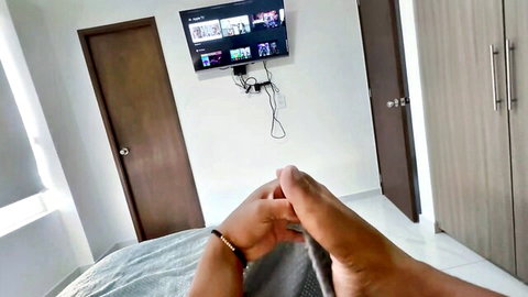 POV closeup of couple's hands locking pinkies intimately on gray bed sheet in bedroom with mounted TV