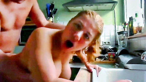 Muscular stud fucks chubby blonde MILF doggy style on kitchen sink, big tits swinging as she orgasms loudly