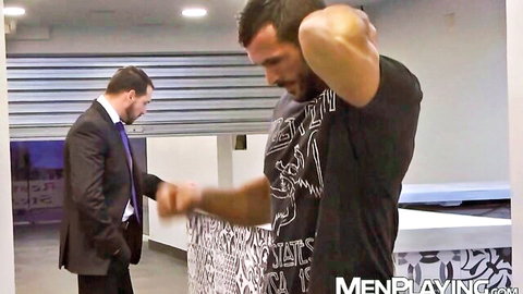 Muscular bodybuilder Denis Vega grabbed by suited man in intense setup