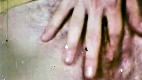 Close-up of woman's pale hand with long red nails spreading open wet hairy pussy lips