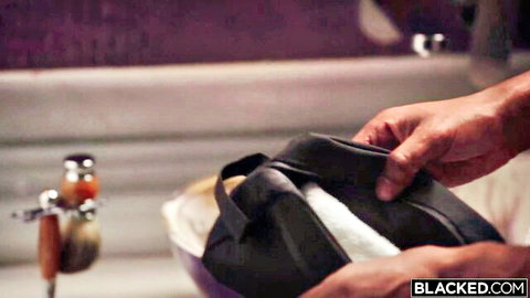 Black hands holding open black duffel bag with white towel in luxurious bathroom sink