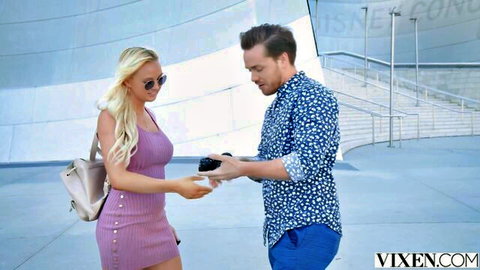 Paisley Porter in pink dress handing phone to man outdoors at landmark