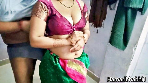 Indian housewife in pink low-cut blouse and green saree groped from behind by man showing deep cleavage and navel