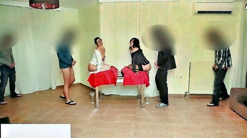 Blured-face sexy women in tiny shorts teasing men around red table