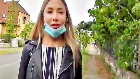 Blonde woman in leather jacket and turquoise mask walking outdoors