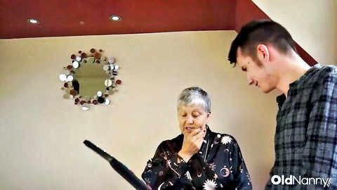 Mature Savana in robe holds dildo with young man watching