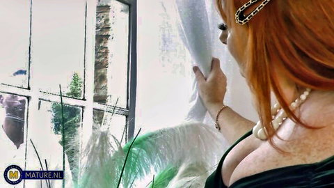 Mature redhead Amber Vixxxen in low-cut green dress with deep cleavage