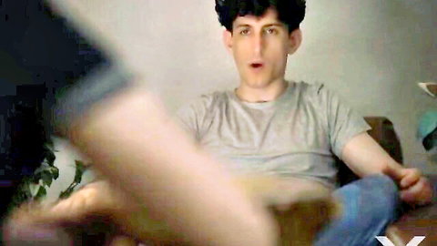 Surprised young guy with hot girl's bare legs in denim shorts draped over his lap on couch