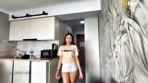 Sexy Asian babe in tight white shorts and betplay t-shirt teasing in kitchen with small tits
