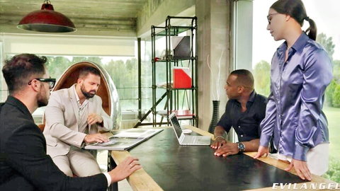 Brunette in shiny satin blouse stands over three suited men at office table