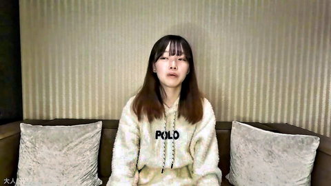 Cute petite Japanese teen with bangs pouting in Polo hoodie on couch