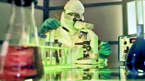 Makayla Cox in quarantine lab suit examining microscope samples
