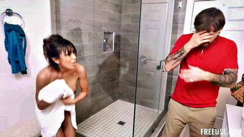 Asian stepmom covering nude body with towel while stepson gestures in bathroom