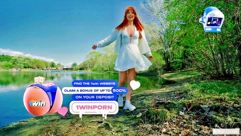 Eva Soda redhead in low-cut white dress walks in sunny park by lake