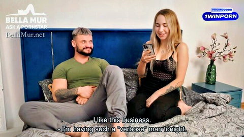 Bella Mur chats with man on bed in Ask a Pornstar interview, blonde in mesh top