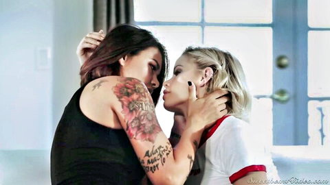 Tattooed brunette and blonde babe passionately kiss in lesbian embrace