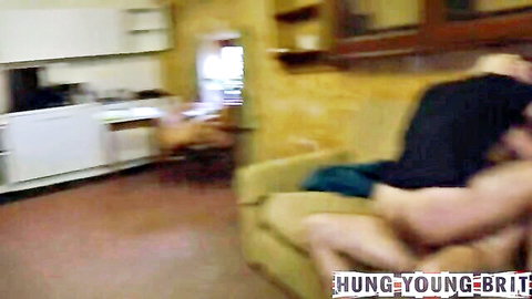 Hung young Brit fucks muscular guy doggy style on yellow couch in kitchen