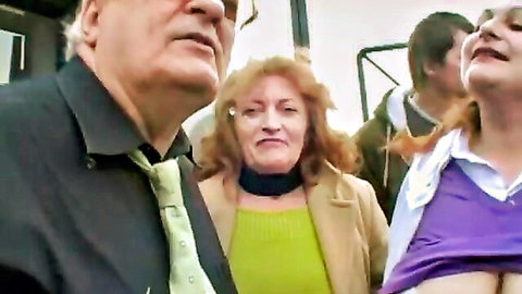 Young woman flashes her bare tits while older man and redhead stare in voyeur scene
