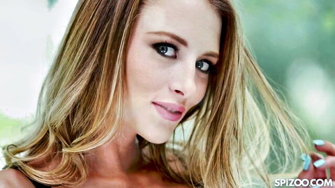 Seductive blonde Kyler Quinn smiling with long wavy hair in green backdrop