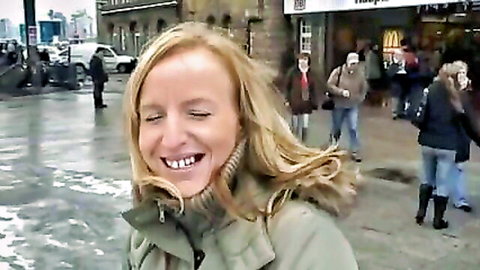 Blonde woman smiling in windy urban street, teasing start to kinky German train sex adventure