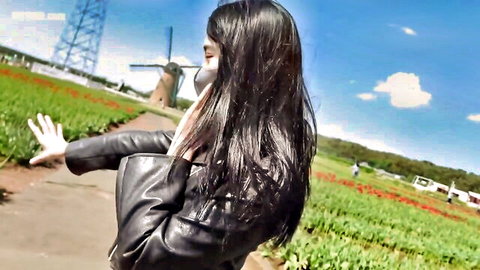 Asian beauty in leather jacket waves in tulip field outdoors