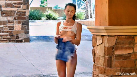 Skinny brunette teen exposes small natural tits and shaved pussy outdoors holding blue shorts