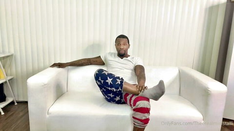 Mini Stallion relaxing in white tee and flag pants, OnlyFans bisexual preview with Hazel Moore