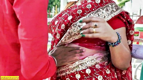 Indian couple in red saree and shirt, intimate waist touch by man on woman