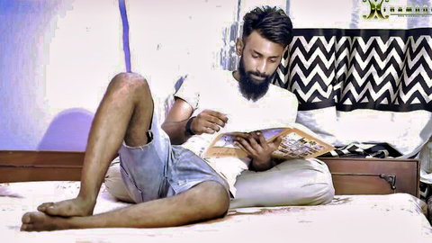 Bearded Indian builder lounging on bed reading book before maid encounter
