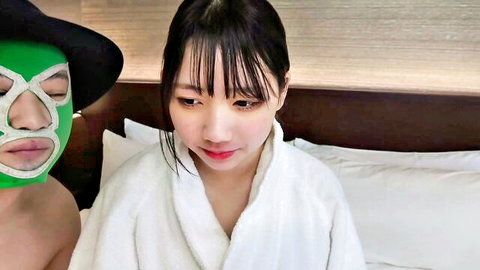 Asian woman in white robe with masked man on bed, teasing encounter