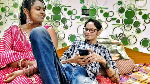 Desi stepmom in red saree smiles with stepson-in-law on bed