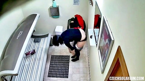 Brunette masturbating in solarium, bent over with pants down
