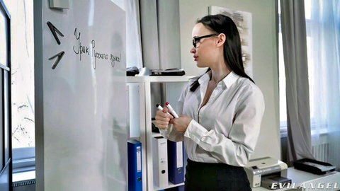 Sexy brunette teacher in glasses and unbuttoned blouse writes on whiteboard showing cleavage