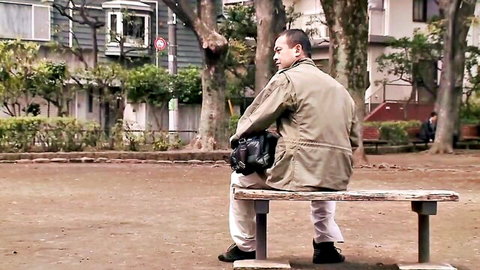 Asian man in jacket waits on park bench for Taiwan escort meetup