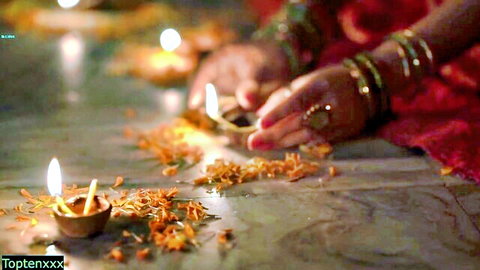 Indian woman in red sari lighting diyas with marigolds, traditional festival tease