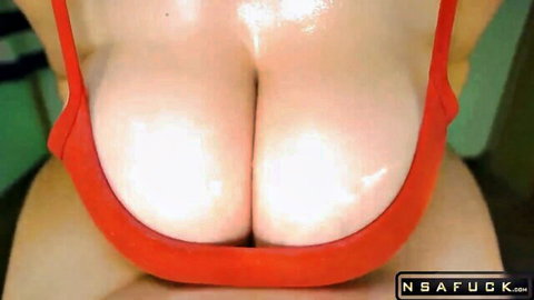 Busty woman in red bra with oiled cleavage during big tits massage