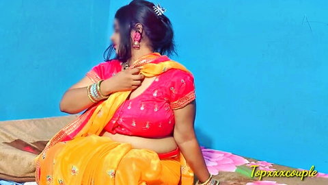 Curvy Desi cougar in red blouse and yellow sari poses seductively on bed