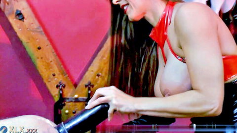 Busty brunette in red latex slides huge black dildo into anal hole