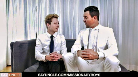Young blond missionary boy in suit chats with suited priest on couch