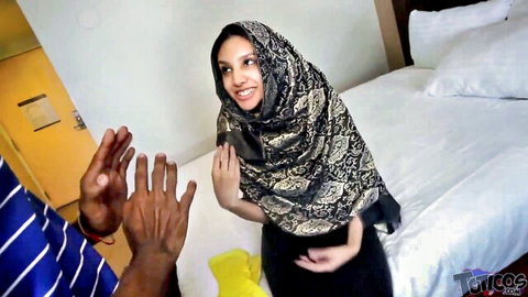 Shy Arab maid in hijab smiles at black man reaching out