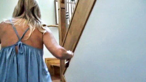 Jodi West blonde MILF in blue halter dress ascending stairs