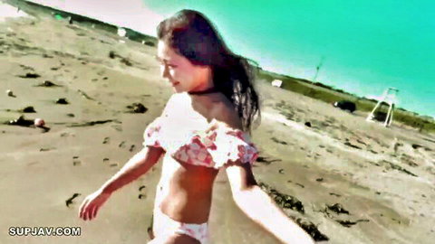 Japanese woman in ruffled white bikini walking on beach