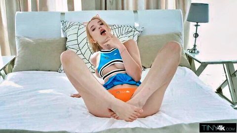 Skinny blonde teen cheerleader spreads legs wide exposing big tits and orange panties on bed