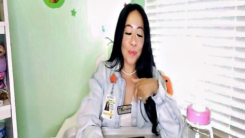 Sexy Asian babe in open denim jacket flashing deep cleavage and smiling in nursery room