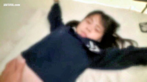 Neat young Asian lady with long black hair lying relaxed on bed in sweater