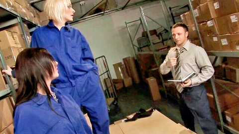 Blonde and brunette in blue overalls with businessman in warehouse foursome tease