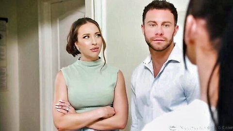 Blonde MILF arms crossed in green top eyeing muscular stud as brunette watches from behind