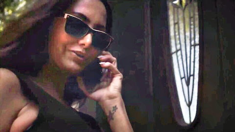 Sexy brunette in sunglasses talking on phone, showing cleavage