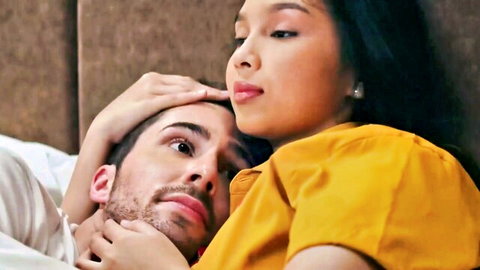 Intimate embrace of Asian woman in yellow top and bearded man in bed